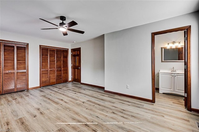 unfurnished bedroom with light wood-type flooring, baseboards, multiple closets, and ensuite bathroom