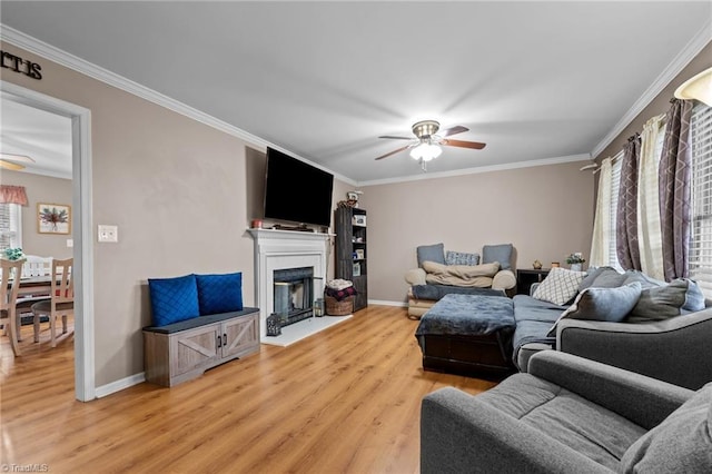 living room with crown molding, light wood-style flooring, and ceiling fan