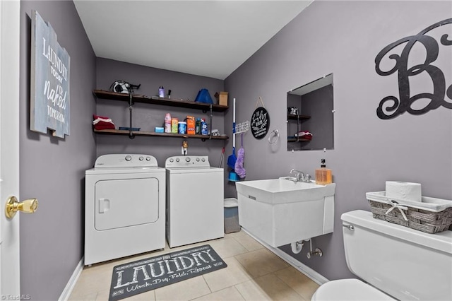 washroom featuring washing machine and clothes dryer, laundry area, baseboards, and light tile patterned floors