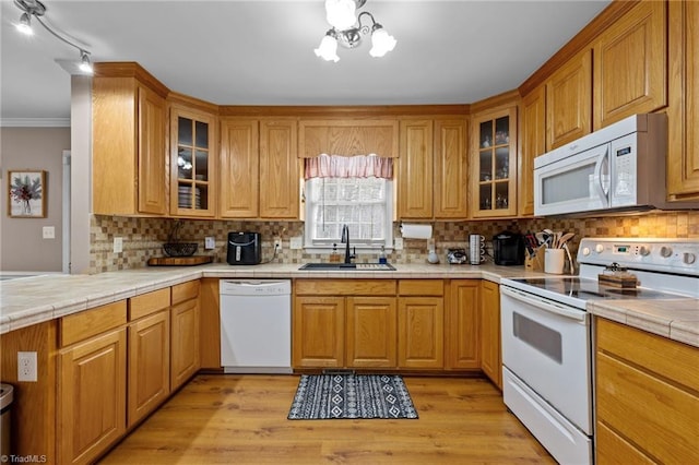 kitchen with a sink, white appliances, backsplash, and light wood finished floors