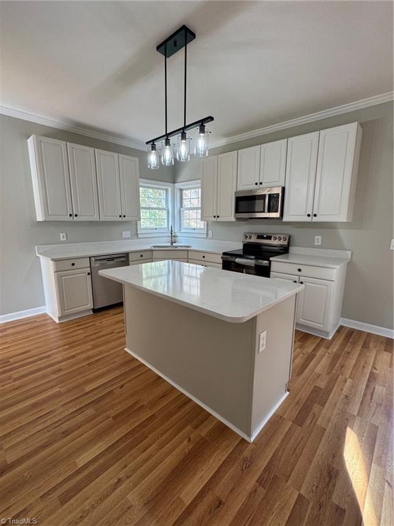 kitchen with stainless steel appliances, white cabinets, pendant lighting, a kitchen island, and light wood-type flooring