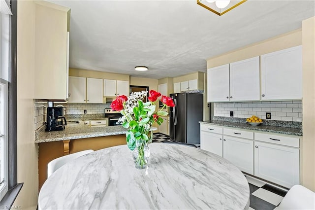 kitchen with appliances with stainless steel finishes, backsplash, light stone counters, and white cabinets