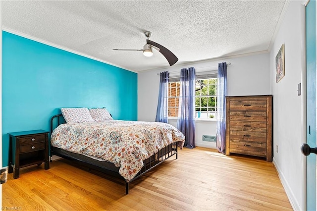 bedroom with light wood-style flooring, ornamental molding, a textured ceiling, ceiling fan, and baseboards