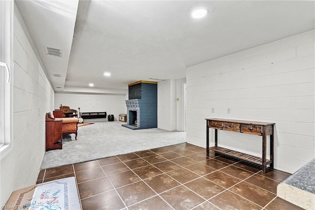 living area featuring a brick fireplace, dark tile patterned flooring, concrete block wall, and recessed lighting