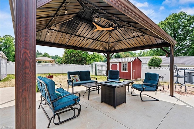 view of patio / terrace featuring a shed, a fenced backyard, an outdoor structure, and an outdoor living space with a fire pit