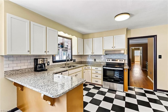 kitchen featuring stainless steel electric range oven, a sink, dark flooring, and plenty of natural light