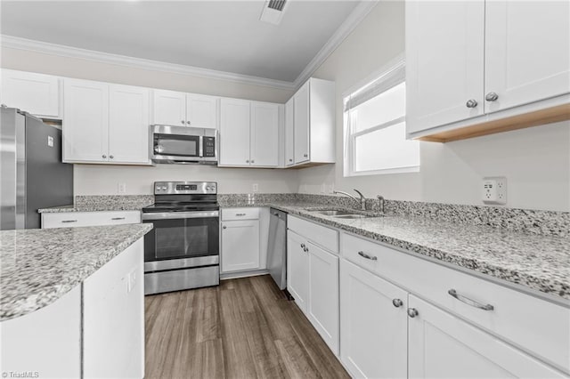 kitchen featuring dark wood-type flooring, stainless steel appliances, crown molding, white cabinetry, and a sink