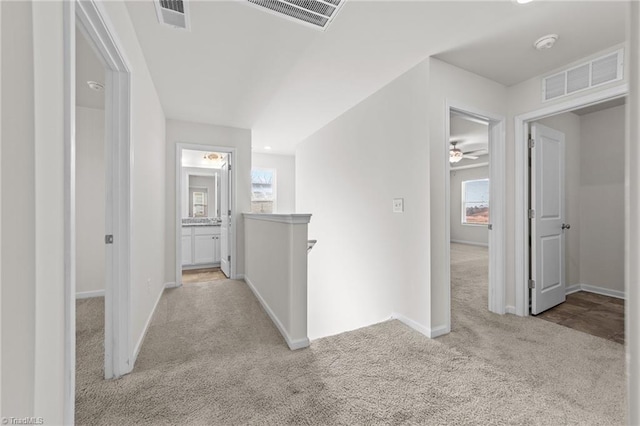 corridor featuring light carpet, visible vents, and an upstairs landing