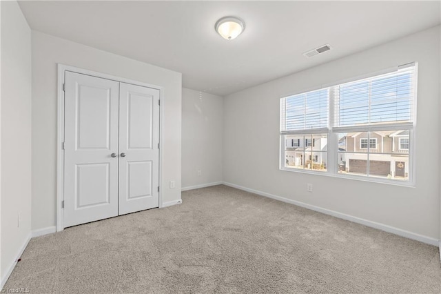 unfurnished bedroom with baseboards, a closet, visible vents, and light colored carpet