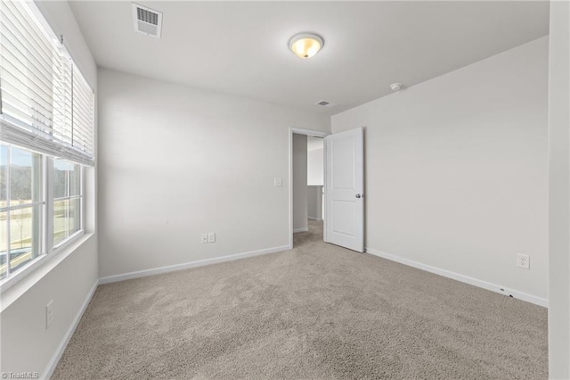 unfurnished room with carpet flooring, visible vents, and baseboards