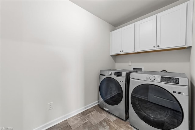 clothes washing area featuring cabinet space, stone finish flooring, baseboards, and washer and dryer