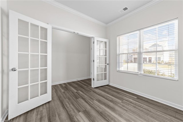 empty room with baseboards, visible vents, dark wood-style flooring, crown molding, and french doors