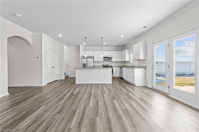 kitchen featuring light wood-style flooring, stainless steel appliances, white cabinetry, a center island, and decorative light fixtures