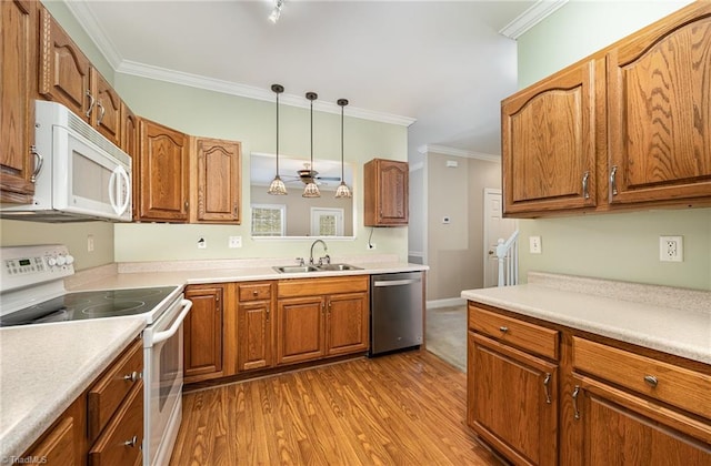 kitchen featuring white appliances, a sink, light countertops, brown cabinetry, and pendant lighting