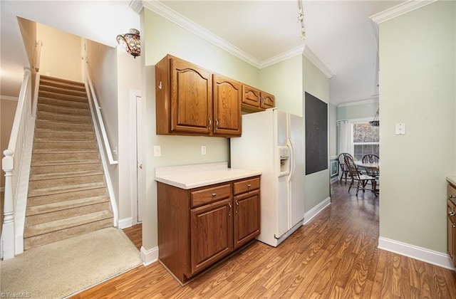 kitchen with wood finished floors, light countertops, brown cabinets, white fridge with ice dispenser, and crown molding