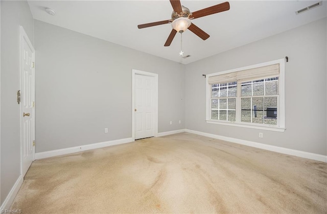 carpeted spare room featuring baseboards, visible vents, and a ceiling fan