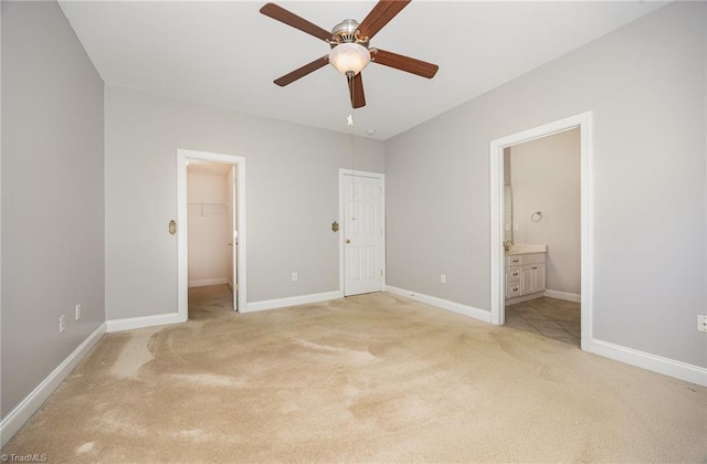 unfurnished bedroom featuring light carpet, connected bathroom, and baseboards