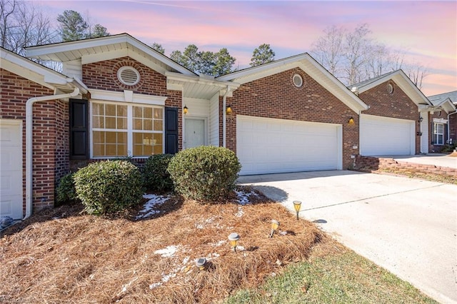 single story home with a garage, driveway, and brick siding