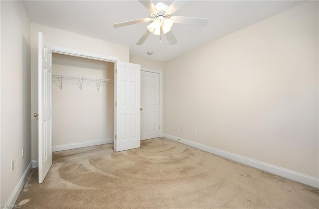 unfurnished bedroom featuring a closet, light carpet, ceiling fan, and baseboards