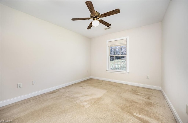 spare room with baseboards, visible vents, a ceiling fan, and light colored carpet