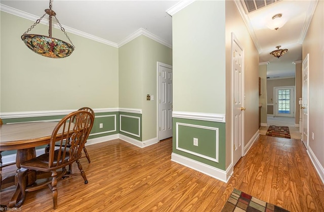 dining space with ornamental molding and light wood-style flooring