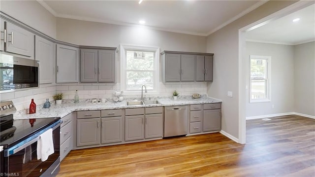 kitchen with gray cabinetry, a sink, stainless steel appliances, and light wood-style floors