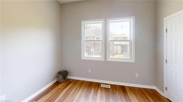 empty room featuring visible vents, wood finished floors, and baseboards