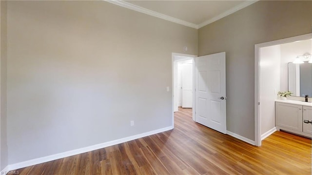 unfurnished bedroom with crown molding, ensuite bath, wood finished floors, and baseboards