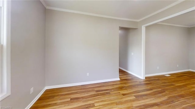 spare room with baseboards, wood finished floors, and crown molding