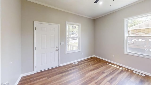 interior space featuring wood finished floors, crown molding, visible vents, and baseboards