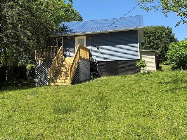back of house featuring metal roof, a deck, a yard, and stairway