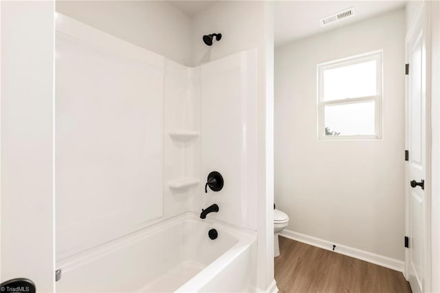 bathroom featuring wood-type flooring, shower / bathtub combination, and toilet