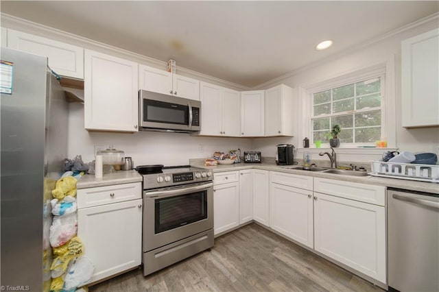 kitchen featuring appliances with stainless steel finishes, sink, white cabinets, and light hardwood / wood-style flooring