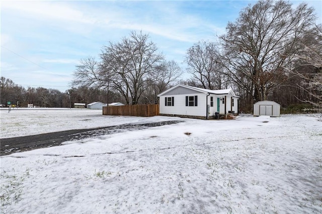 snowy yard featuring a storage unit