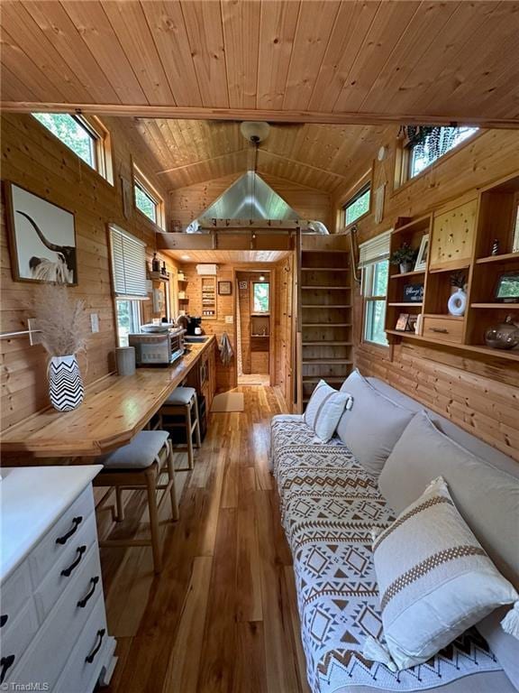 interior space with wooden walls, light hardwood / wood-style flooring, wood ceiling, and vaulted ceiling