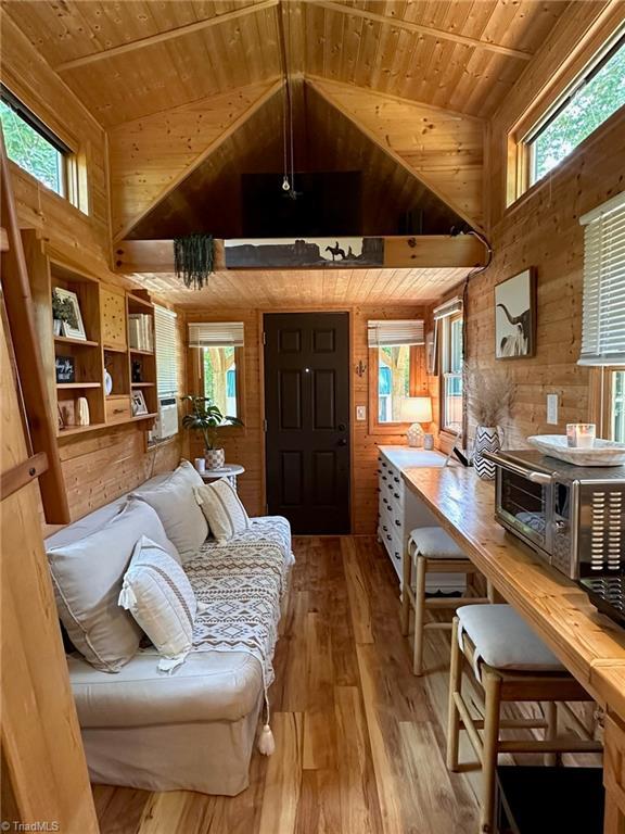 living room featuring wood ceiling, wood walls, and a healthy amount of sunlight