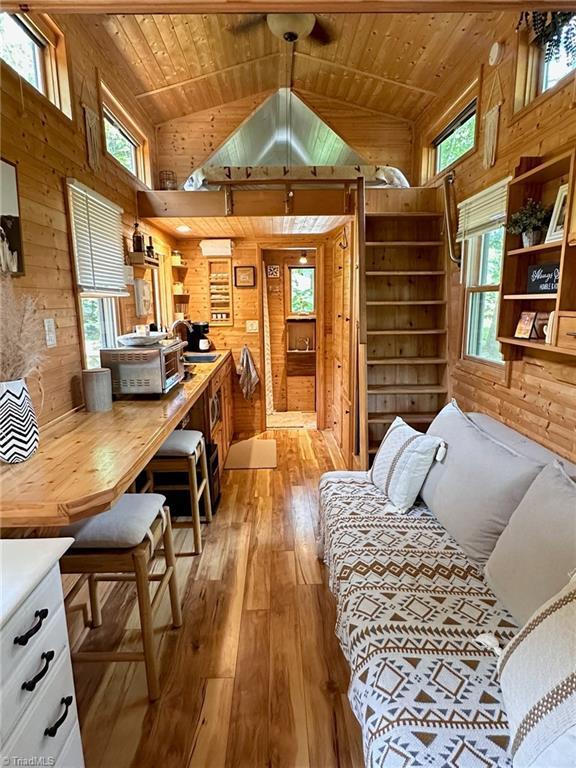 interior space with high vaulted ceiling, wooden ceiling, light hardwood / wood-style flooring, and wooden walls