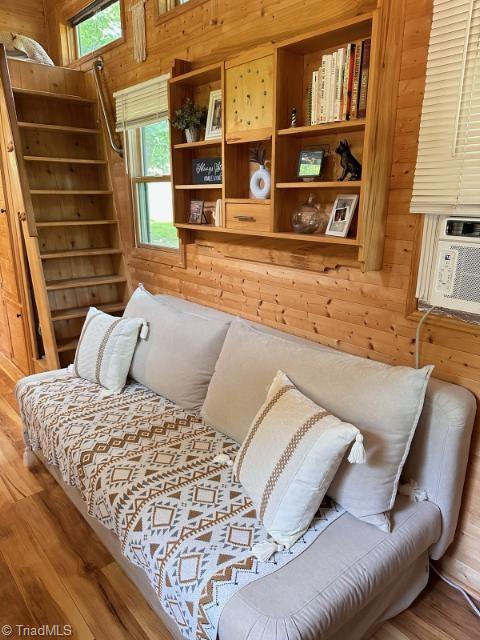 sitting room with wood-type flooring, cooling unit, and wooden walls