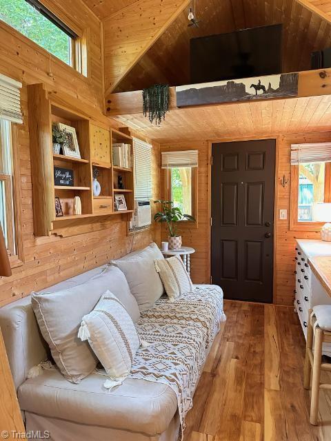 living room with wood walls, wooden ceiling, vaulted ceiling, and hardwood / wood-style flooring