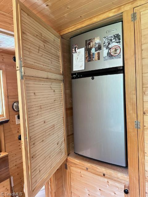 interior details featuring stainless steel fridge, wooden walls, and wood ceiling