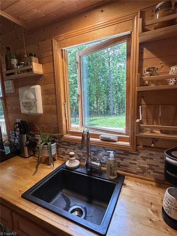 interior space with butcher block countertops, wood ceiling, sink, and wooden walls