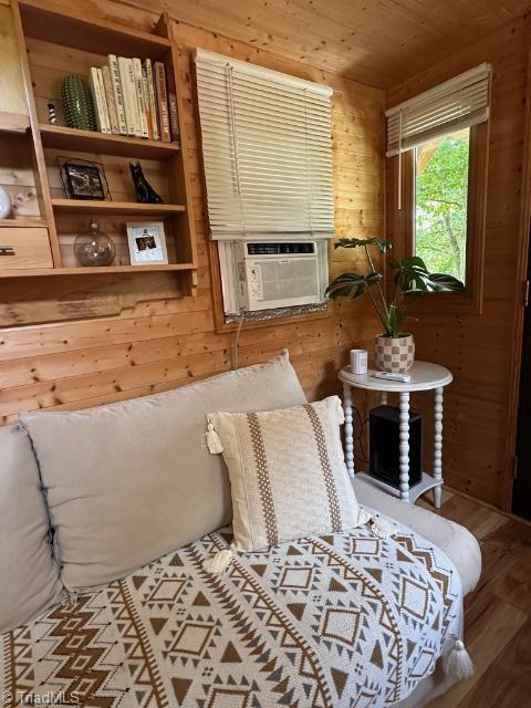 sitting room featuring hardwood / wood-style flooring, wood walls, and wood ceiling