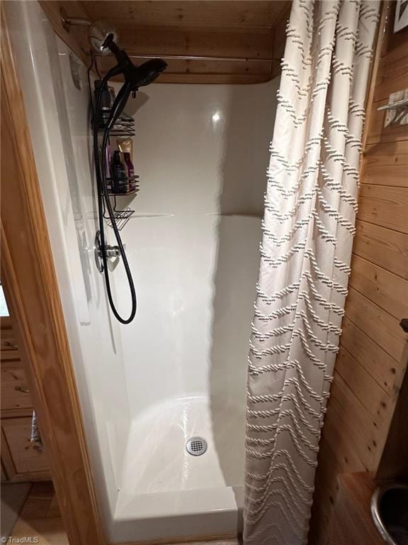 bathroom with a shower with curtain and wood walls