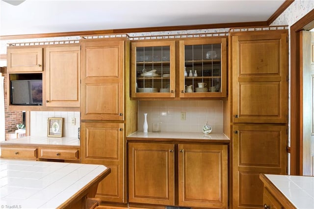 102 Shawnee Cir, Lexington, NC 27295 - kitchen with tile countertops, tasteful backsplash, glass insert cabinets, crown molding, and brown cabinets