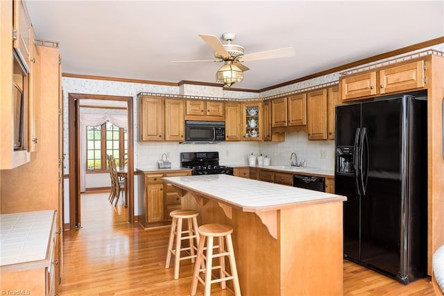 102 Shawnee Cir, Lexington, NC 27295 - kitchen featuring tile counters, black appliances, ornamental molding, light wood-style floors, and a kitchen bar