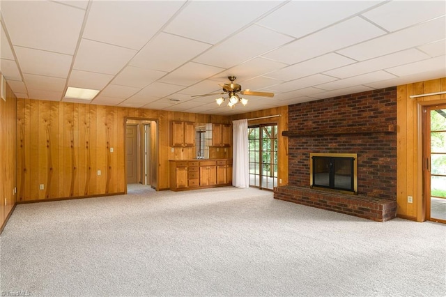 102 Shawnee Cir, Lexington, NC 27295 - unfurnished living room with wood walls, healthy amount of natural light, light carpet, a ceiling fan, and a fireplace