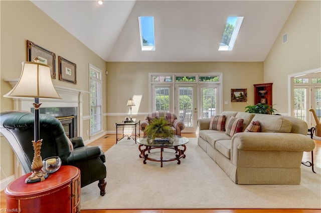 4208 Bitternut Trl, Greensboro, NC 27410 - living area featuring a skylight, high vaulted ceiling, french doors, a glass covered fireplace, and wood finished floors