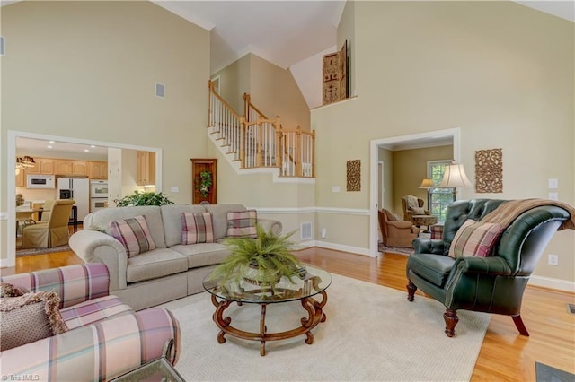 4208 Bitternut Trl, Greensboro, NC 27410 - living area featuring a towering ceiling, stairs, light wood-style flooring, and baseboards