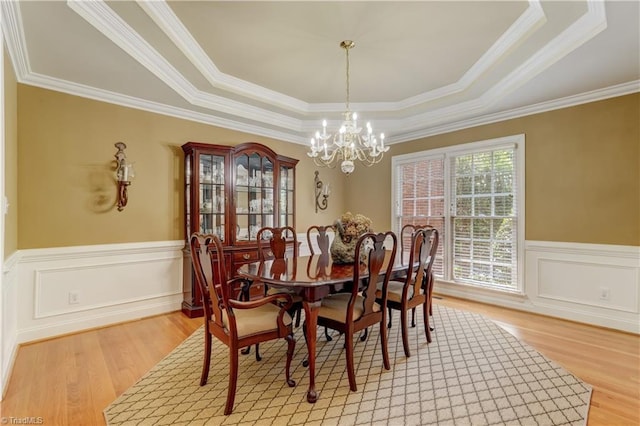 4208 Bitternut Trl, Greensboro, NC 27410 - dining area featuring a raised ceiling, a chandelier, light wood-style flooring, crown molding, and wainscoting