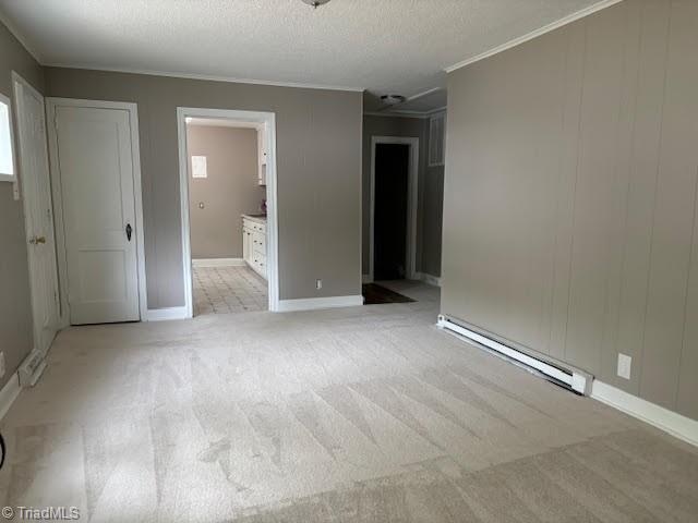 carpeted empty room with a baseboard radiator, ornamental molding, and a textured ceiling